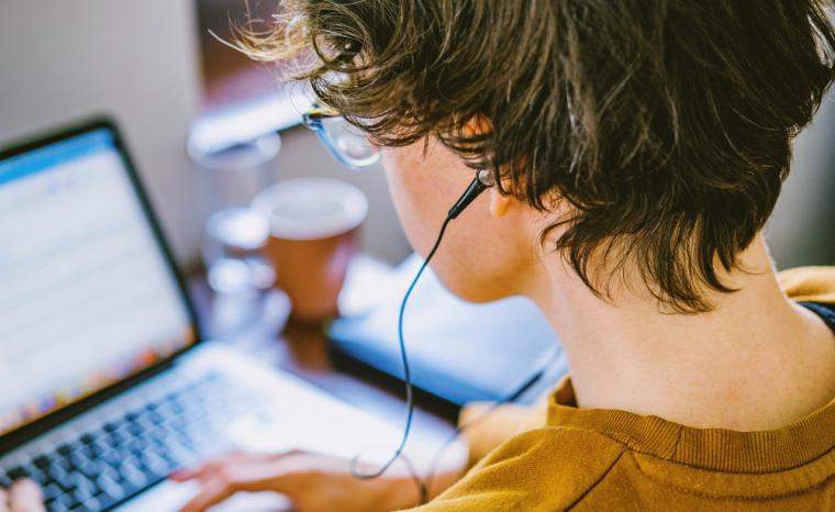 Una mujer utiliza un ordenador port&aacute;til con unos auriculares conectados