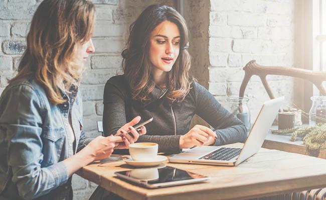 Dos mujeres hablan con un m&oacute;vil en la mano mientras trabajan