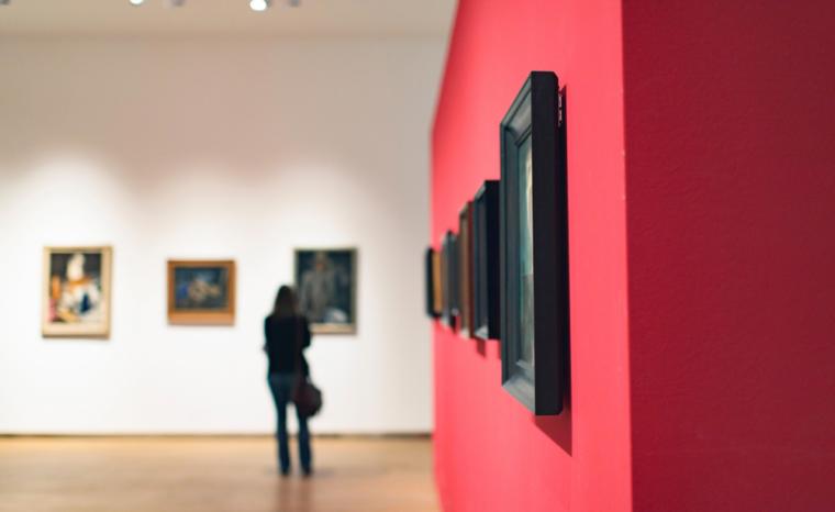 Fotograf&iacute;a del interior de un museo con una persona viendo un cuadro al fondo