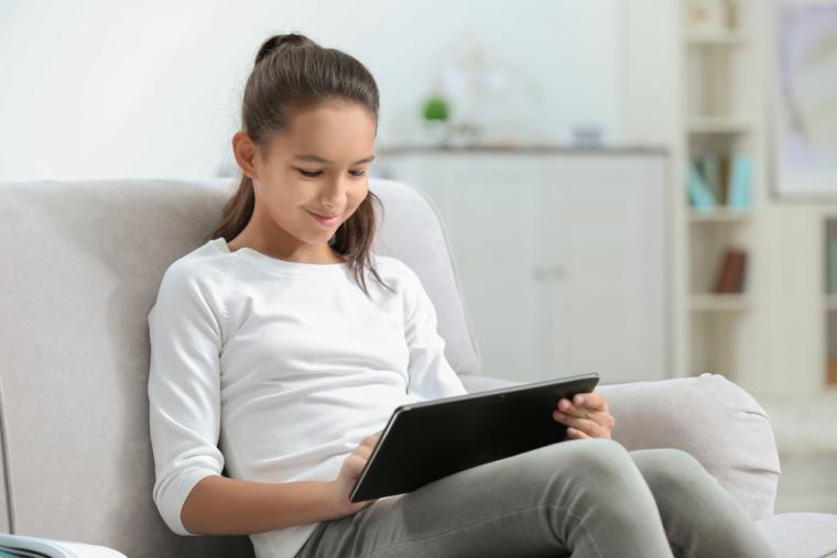 Una joven utiliza una tableta sentada en un sof&aacute;