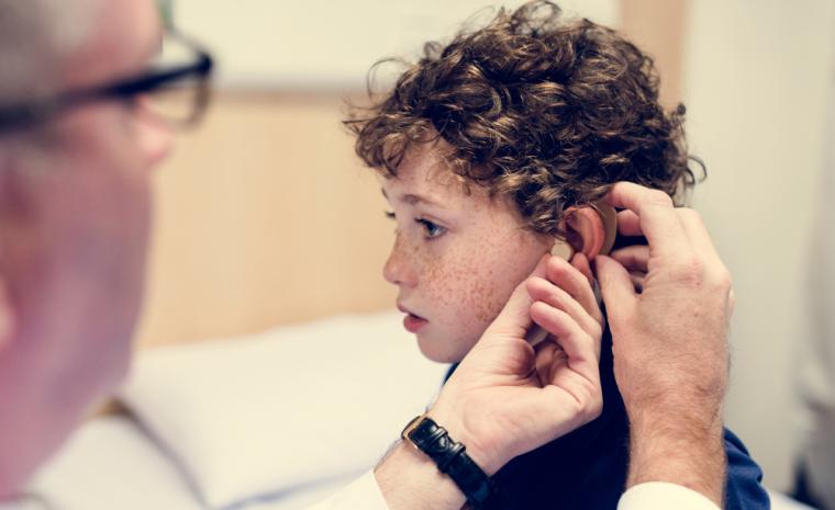 Un doctor coloca una pr&oacute;tesis a un ni&ntilde;o con discapacidad auditiva