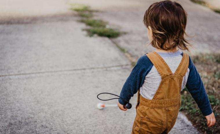 Un ni&ntilde;o con discapacidad visual camina por la calle con un bast&oacute;n rojo y blanco