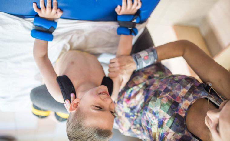 Un ni&ntilde;o con par&aacute;lisis cerebral durante una sesi&oacute;n de rehabilitaci&oacute;n. La fotograf&iacute;a est&aacute; al rev&eacute;s para sumarse a la campa&ntilde;a "Dale la Vuelta" de Aspace.