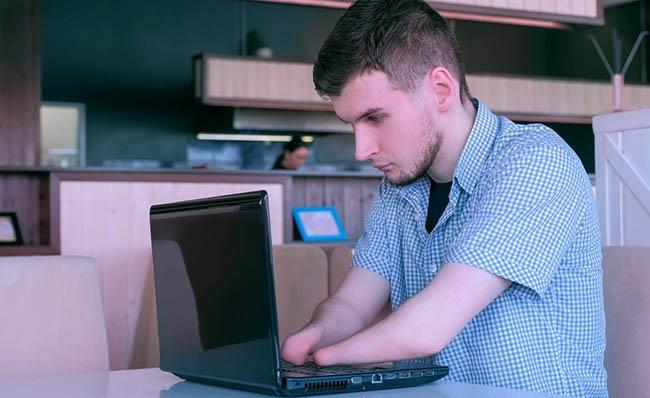 Un joven con discapacidad utiliza un ordenador port&aacute;til
