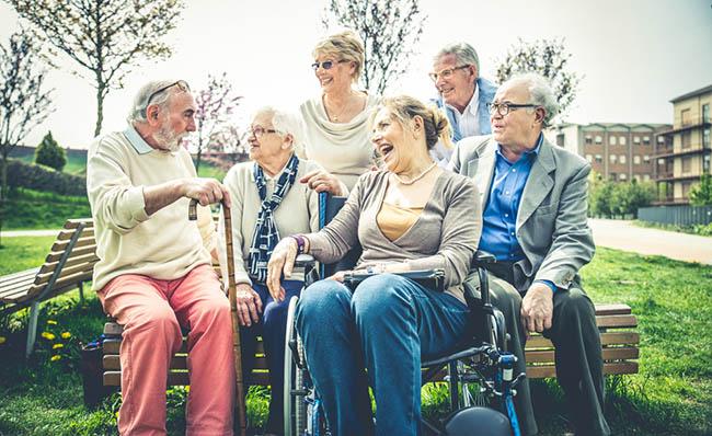 Varias personas mayores sentadas alrededor de un banco