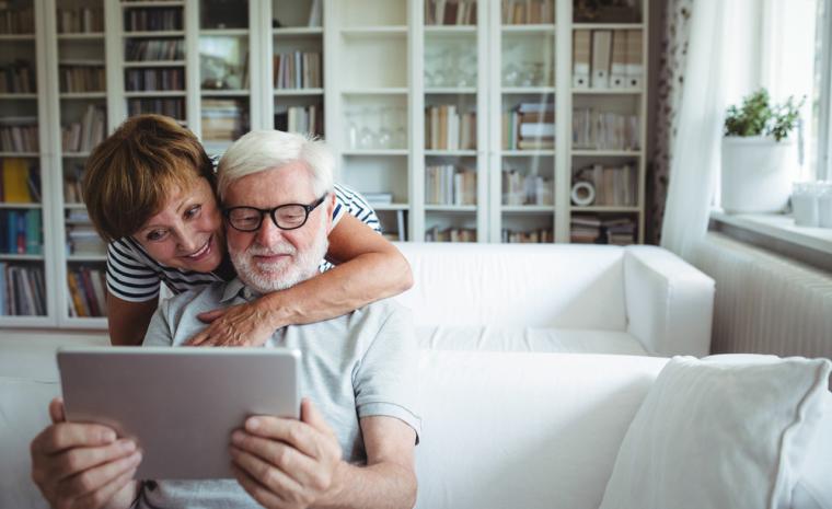 Una pareja de personas mayores utiliza una tableta en su sal&oacute;n