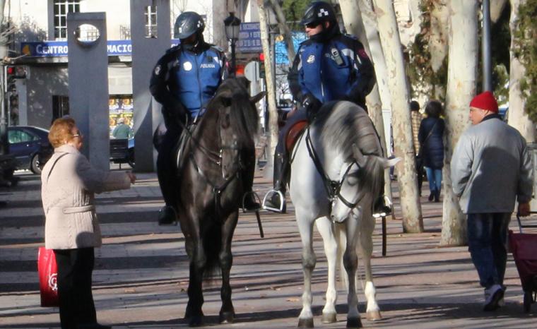 Dos Polic&iacute;as Municipales de Madrid a caballo hablan con una mujer