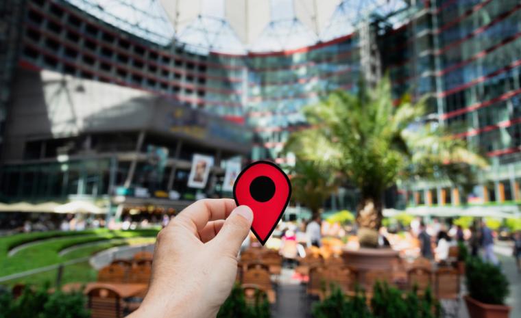 Una persona sujeta con la mano una se&ntilde;al t&iacute;pica de aplicaciones de localizaci&oacute;n dentro de un edificio