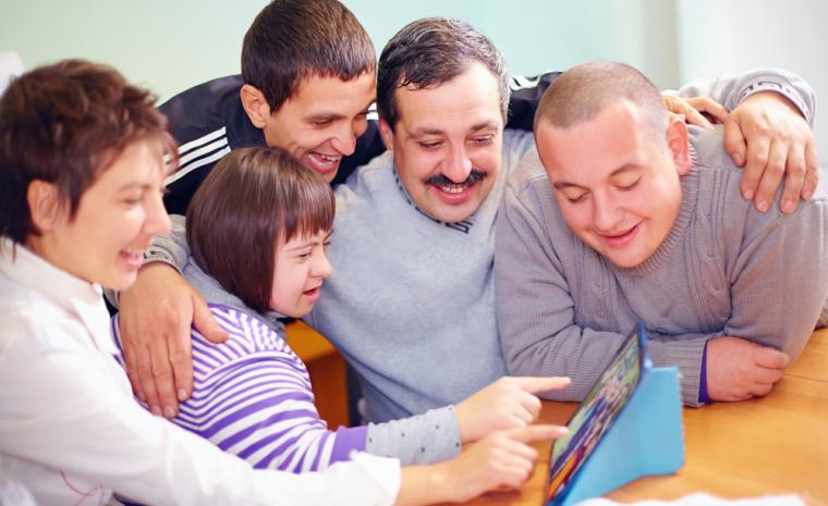 Varias personas con discapacidad miran y se divierten utilizando una tableta