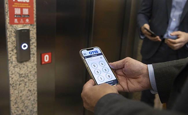 Imagen de una persona utilizando la app Pulse en su m&oacute;vil delante de un ascensor