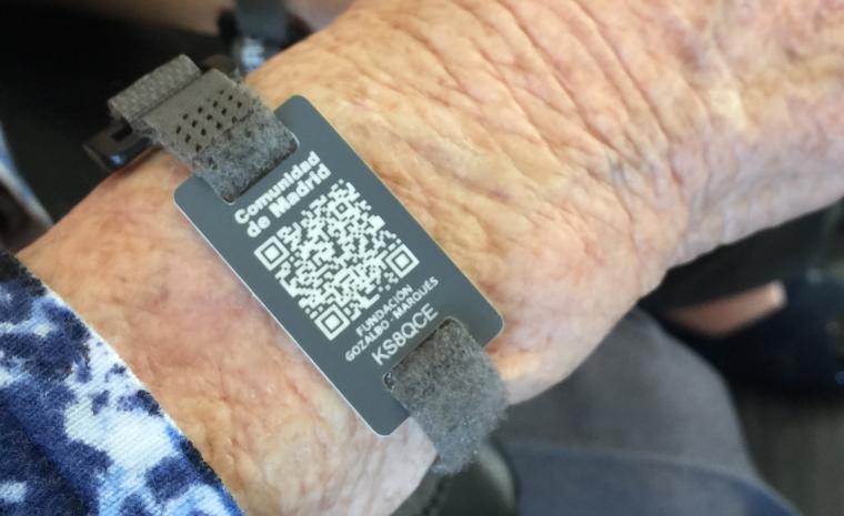 Detalle de una pulsera con c&oacute;digo QR en la mu&ntilde;eca de una mujer mayor