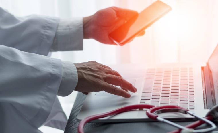 Un doctor utiliza un ordenador y un m&oacute;vil