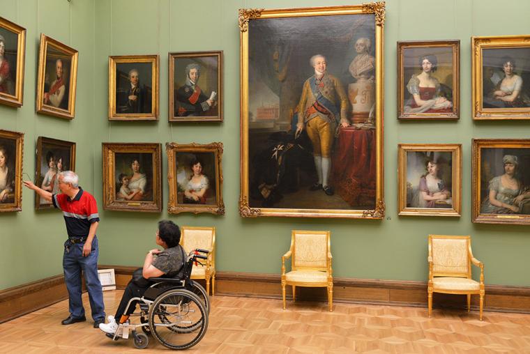 Una mujer en silla de ruedas visita una exposici&oacute;n en un museo