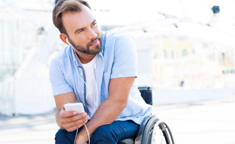 Un j&oacute;ven en silla de ruedas utiliza su tel&eacute;fono m&oacute;vil