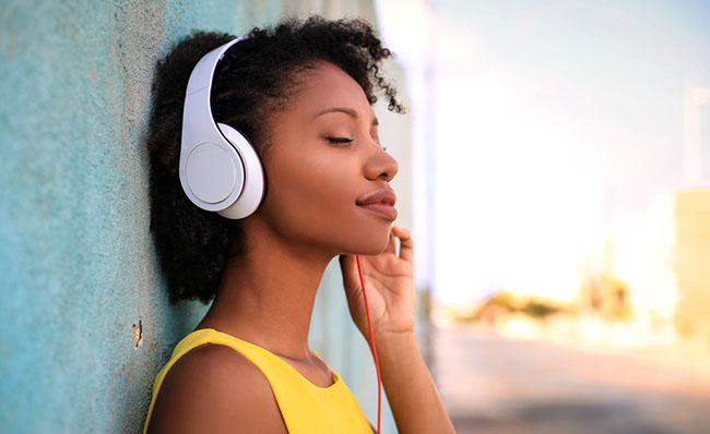 Una mujer escucha m&uacute;sica a trav&eacute;s de su smartphone con unos auriculares