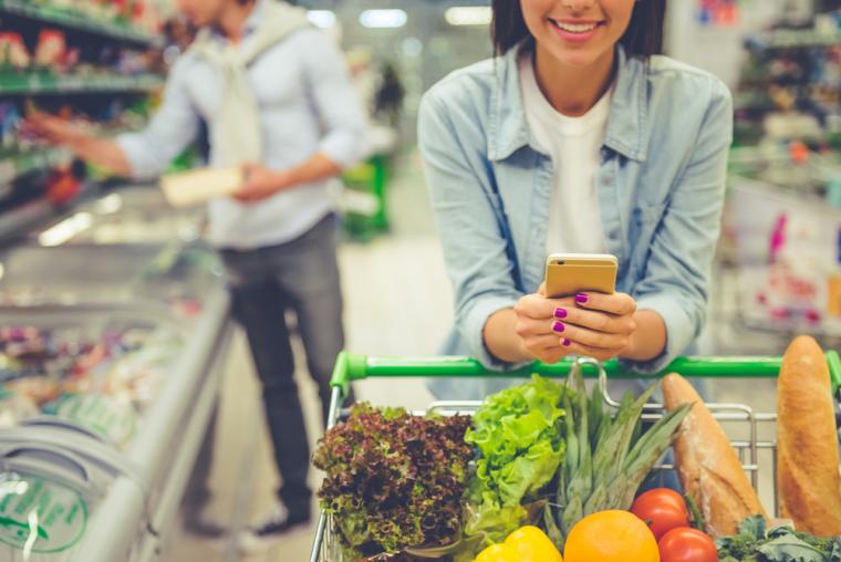 Una mujer utiliza su smartphone mientras hace la compra