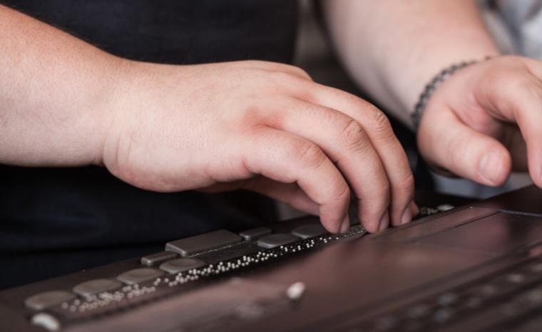 Una persona ciega utiliza la l&iacute;nea braille conectada a un ordenador port&aacute;til