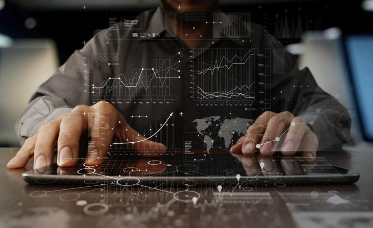 Un hombre maneja una tableta con infograf&iacute;a de tablas y gr&aacute;ficos por encima