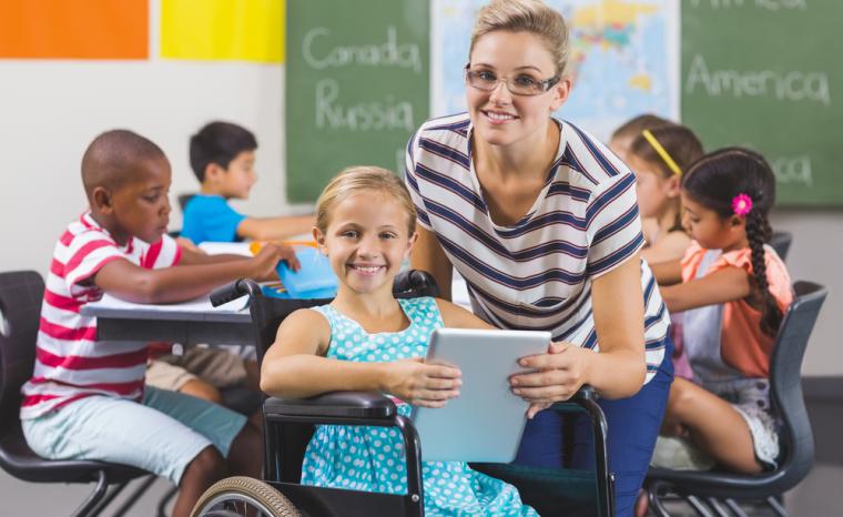 Una profesora y una alumna en silla de ruedas utilizan una tableta