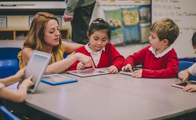 Una profesora trabaja con varios ni&ntilde;os utilizando tecnolog&iacute;a