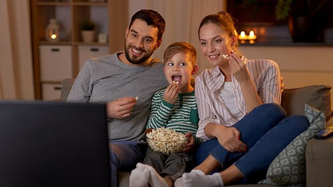 Una familia ve la televisi&oacute;n sentada en un sof&aacute;