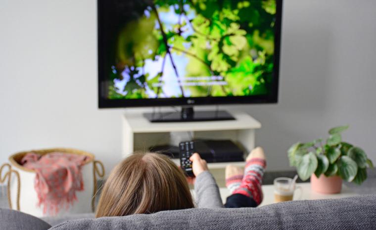 Una persona ve la televisi&oacute;n en el sof&aacute; utilizando subt&iacute;tulos