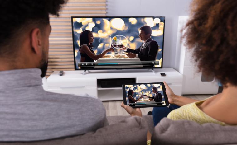 Dos j&oacute;venes ven la televisi&oacute;n en el televisor y en un m&oacute;vil