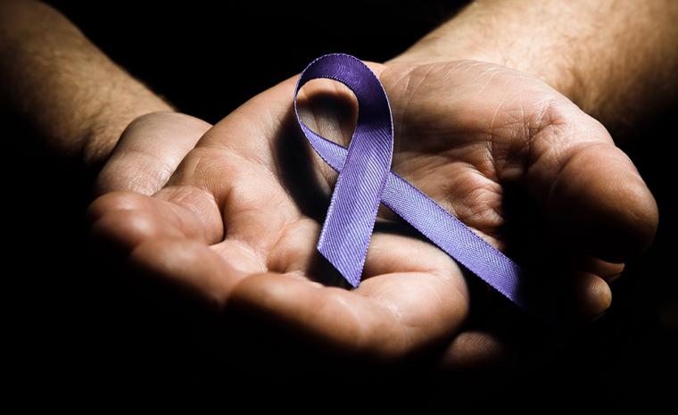 Unas manos sujetan un lazo morado contra la violencia machista