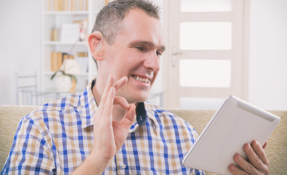 Un hombre con audífono se comunica a través de una tableta