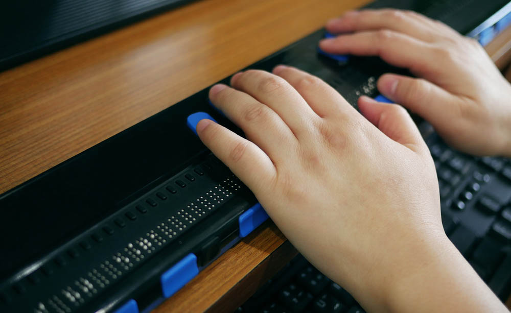 Una personas utiliza una línea braille con su ordenador