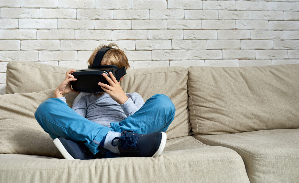 Un niño utiliza unas gafas de realidad virtual sentado en un sofá